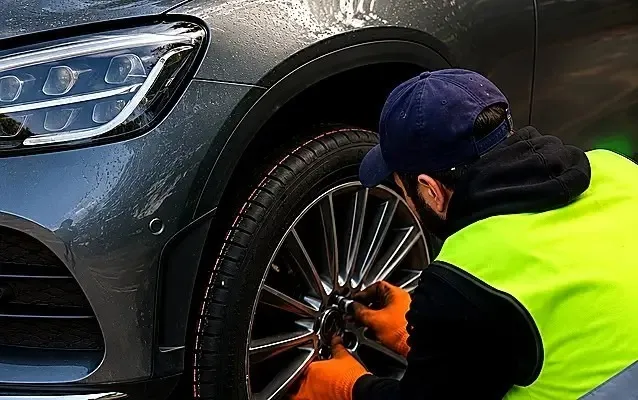 Technician inspecting a car tyre tread and sidewall condition during a mobile tyre check in the UK
